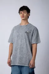 Remera gris con efecto acid wash, corte holgado y estampa frontal con una mano sosteniendo el mundo VCP.