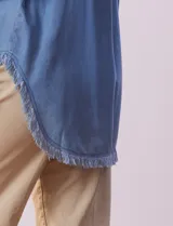 Camisa celeste de tencel marca Hester & Orchand, con cuello con solapa, escote en V y abertura central con botones. Tiene un bolsillo aplicado en la delantera y ruedo desflecado.