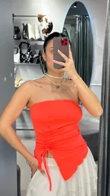 Top strapless color fucsia neón con frunces laterales y corte irregular en el ruedo.