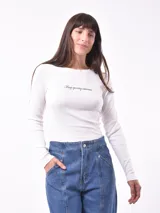 Remera blanca de manga larga con cuello redondo y estampado pequeño con la frase 'Busy ignoring someone' en el pecho.