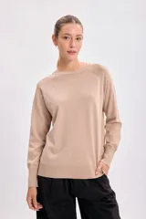 Sweater color beige de tejido de punto, con cuello redondo y mangas largas.