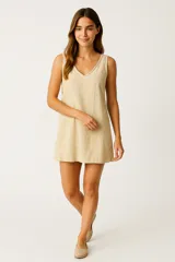 Vestido corto color beige, de corte recto y sin mangas, con escote en V.