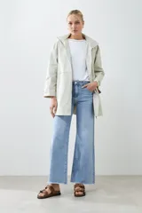 Campera impermeable gris claro con capucha plegable y bolsillos laterales.