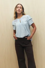Blusa blanca de tela liviana con mangas cortas con volados y botón de nácar.