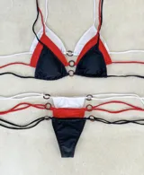 Conjunto de bikini tricolor (blanco, rojo y negro) con tiras finas y detalles de aros metálicos.