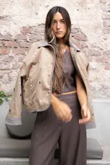 Cazadora color beige con apliques de pedrería y detalles en color marrón.