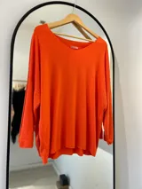 Sweater naranja de tejido de punto, manga larga y escote en pico.