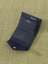 Billetera pequeña color visón, con solapa y cierre a presión. Diseño acolchado con pespuntes en forma de V y logo metálico con forma de labios.