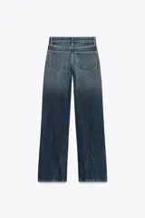 Pantalón de jean azul oscuro, de tiro bajo, corte wide leg y largo hasta el tobillo.