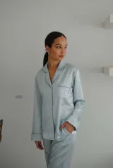 Pijama de satén celeste con vivos en contraste. Incluye camisa de manga larga con botones y pantalón recto con elástico y lazo en la cintura.