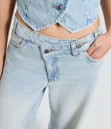 Pantalón de jeans azul de corte wide leg, tiro medio, con cintura de diseño traspasado y cierre tradicional.