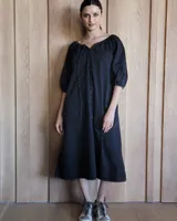 Vestido midi celeste de denim, con escote con lazo, mangas 3/4 abullonadas y corte evasé.
