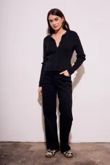 Cardigan negro de punto con cuello polo, manga larga y cierre frontal con botones.