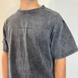 Remera gris con efecto lavado y estampado de una fotografía de la playa en la espalda. Corte oversize.