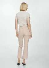 Pantalón de jean color beige, de corte flare, tiro alto y largo crop con terminación desflecada.