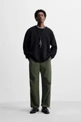 Pantalón verde militar de corte relaxed fit confeccionado en tejido técnico ligero. Cuenta con cintura elástica ajustable con cordón interior, bolsillos frontales y traseros con solapa, pliegues en las rodillas y bajo ajustable con elástico.