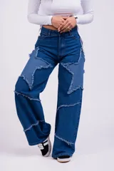 Pantalón de jean azul con parches en forma de estrella de un tono más claro y bordes desflecados.