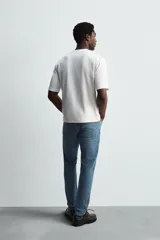 Pantalón de jean negro, corte slim fit, con tiro medio, cinco bolsillos, efecto lavado y cierre frontal con cremallera y botón.