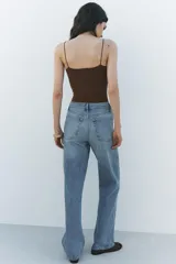 Pantalón de jean celeste de tiro alto, corte recto y largo hasta el tobillo. Tiene cinco bolsillos, trabillas en la cintura, efecto lavado y cierre frontal con cremallera y botón.