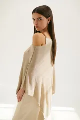 Poncho color beige de tejido de punto con cuello asimétrico.