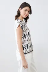 Blusa de manga corta con estampado geométrico en tonos beige, blanco y negro.