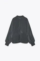 Camisa gris confeccionada en seda 100%, de cuello redondo y manga larga abullonada con puño. Cierre frontal con botones ocultos por solapa.