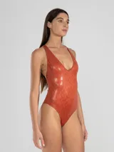 Malla entera color ladrillo con estampado de piel de serpiente, escote en V y espalda descubierta con tiras cruzadas unidas por un detalle metálico cuadrado.