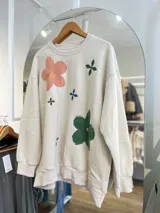 Buzo color beige con cuello redondo y puños acanalados. Estampado con flores de colores y hojas.