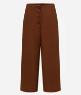 Pantalón tipo pantacourt (largo por encima del tobillo) color marrón, confeccionado en tejido de liocel. Presenta cintura con elástico en la parte trasera y una hilera de botones forrados en la parte delantera.