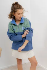 Buzo verde y azul con cierre metálico y bordados de flores.