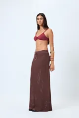 Falda larga tejida color crema, con trama calada de punto abierto y cordón ajustable en la cintura.