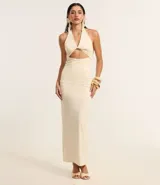 Vestido largo color crema, de tejido jersey, con escote halter y detalle de nudo/torcido en el busto que genera un recorte cutout central. El vestido es ajustado al cuerpo.
