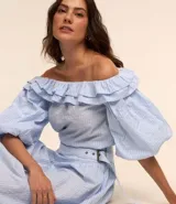 Blusa con escote hombro a hombro, confeccionada en tricolina con estampa rayada, volados en el escote y mangas cortas amplias.