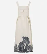 Vestido midi de corte evasé, color crema, con escote cuadrado y breteles anchos. Presenta un estampado grande de hojas y follaje en tonos oscuros en el ruedo inferior.