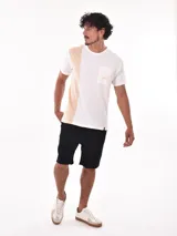 Remera negra de corte oversized con bolsillo en el pecho y detalle de bloque gris en el lateral.