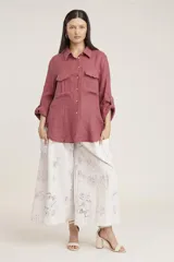 Camisa de lino color beige con cuello clásico, cierre frontal con botones, mangas largas con trabillas para enrollar y dos bolsillos con solapa en el pecho.