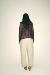 Pantalón color beige de tiro medio con cintura elástica ajustable con cordones, bolsillos delanteros y falsos bolsillos de vivo en la espalda. El bajo es ajustable con botón a presión.