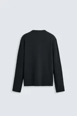 Camiseta blanca de manga larga con cuello redondo y textura cuadriculada.