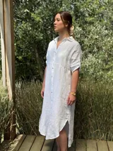 Vestido camisero largo de lino blanco, con corte en la cintura, abertura lateral y botones de nácar.
