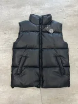 Chaleco puffer negro de cuero sintético con cierre frontal y cuello alto.