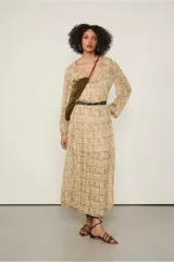 Vestido largo con estampado abstracto en tonos beige y marrón, de mangas largas con puños elásticos, escote en V con volantes y falda evasé con recortes. Incluye cinturón fino negro.