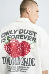 Camisa relaxed fit color blanco crudo, confeccionada en tejido de algodón con estructura. Cuello bowling y manga corta. Estampado frontal con la frase "ONLY DUST IS FOREVER" en negro. Cierre frontal de botonadura.