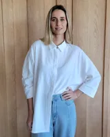 Camisa blanca de corte amplio con mangas largas y cuello clásico.