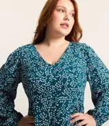Vestido corto de crepé color verde azulado con estampado de mini corazones blancos, escote en pico, mangas largas con puños elásticos y cierre en la espalda.