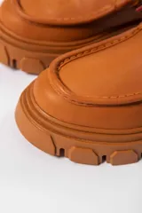 Bota acordonada color suela, con suela track y cordones color naranja.