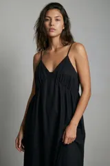 Vestido negro de tirantes finos con escote en V y corte imperio, con falda amplia y holgada.
