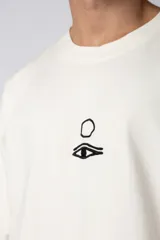 Remera color crudo de corte oversize con estampado pequeño en el centro del pecho.