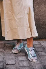 Championes celestes con glitter multicolor en punta y talón, lazo de raso y suela de cuero.