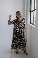 Vestido largo de corte amplio con estampado animal print en tonos negro y beige, cuello camisero y mangas largas.