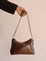 Cartera negra de cuero charol con forma de media luna y correa de cadena metálica plateada.